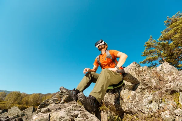 Successful young man, using virtual reality goggles to tour in mountains, on vacation in summer — Stock Photo, Image