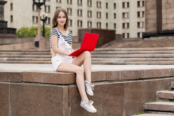 Giovane bella donna con computer portatile seduto sulle scale vicino all'università — Foto Stock