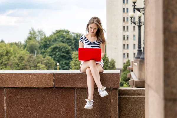 Молодая красивая женщина с ноутбуком сидит на лестнице рядом с университетом — стоковое фото