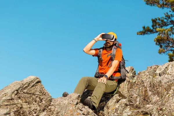 Successful young man, using virtual reality goggles to tour in mountains, on vacation in summer — Stock Photo, Image