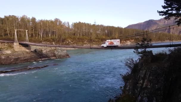 Панорама гірської річки, підвісний міст, бірюзова вода, влітку і восени — стокове відео