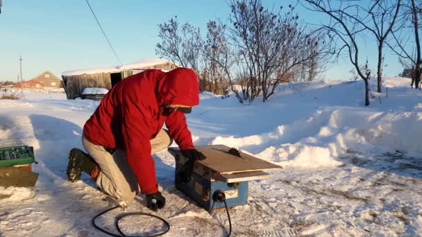 Young man repairing, circular saw, winter on the street, in the countryside — Stock Video