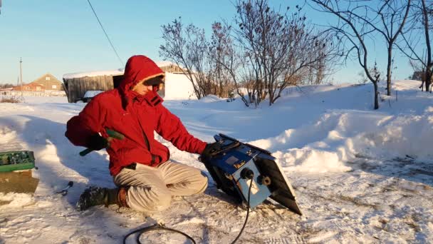 Молодий чоловік ремонтує, циркулярна пилка, зима на вулиці, в сільській місцевості — стокове відео