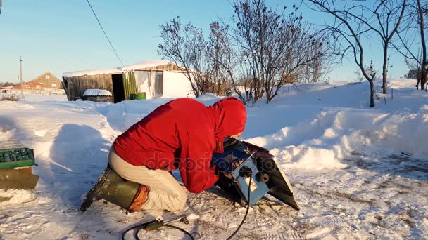 Jeune homme réparateur, scie circulaire, hiver dans la rue, à la campagne — Video