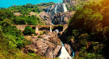 View of the railway bridge in the mountains through the waterfall, India, Goa clipart