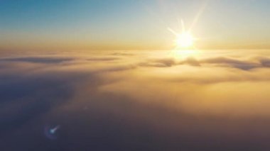 Hava görüntüsü. Sisin içinde uçmak, sisin içinde uçmak. Hava kamerası görüntüsü. Bulutların üzerinden güneşe doğru uç. Sisli hava, yukarıdan manzara.