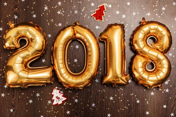 Λαμπερό μεταλλικό χρυσό μπαλόνια αριθμοί 2018, Χριστούγεννα, Πρωτοχρονιά μπαλόνι με Γκλίτερ αστέρια σε τραπέζι από ξύλο σκούρο φόντο — Φωτογραφία Αρχείου