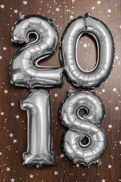 Jasny srebrny metaliczny balony figury 2018, Boże Narodzenie, nowy rok balon z brokat gwiazd na tle ciemnego drewna tabela — Zdjęcie stockowe
