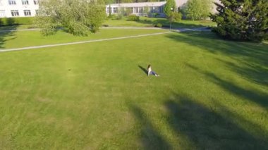 Havadan görünümü. Genç kız yalan ve bahçede çimlerin üzerine park güneşli günde dinlenme. Görünümünün üzerinde. Kadın çayır çim üzerinde. Üstten Görünüm