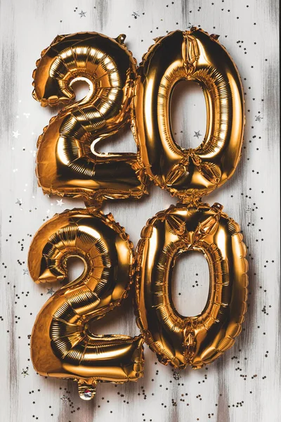 Happy New year 2020 celebration. Bright gold balloons figures, New Year Balloons with glitter stars on wood white background. Christmas and new year celebration. Gold foil balloons 2020 — Stockfoto