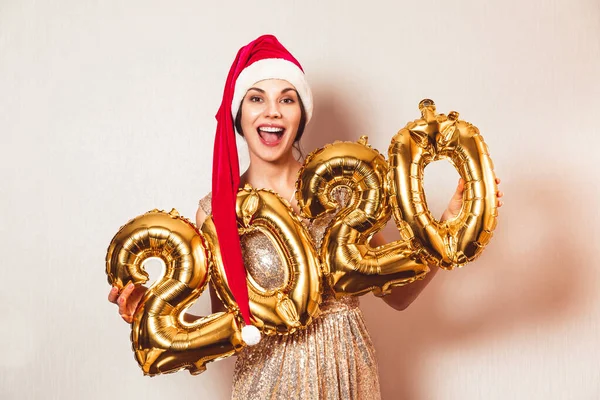 Nouvel An 2020 nombre d'or ballons. Belle femme avec des ballons Célébration du Nouvel An Eve Party. En bonnet rouge du Nouvel An. Fille souriante en robe brillante lumineuse à la célébration — Photo