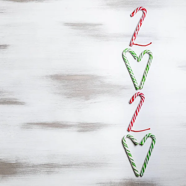 Nuevo año 2020. Feliz Navidad y Felices Fiestas tarjeta de felicitación. Composición navideña. Decoraciones de caramelo rojo y verde sobre fondo blanco madera. Concepto de año nuevo. Plano, vista superior, espacio para copiar —  Fotos de Stock