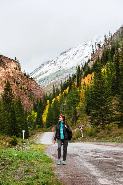 Young girl tourist, photographs on a smartphone, beautiful landscapes, mountains with snow-capped peaks. Woman taking pictures selfie against the backdrop of beautiful mountain landscape — Stock Photo, Image