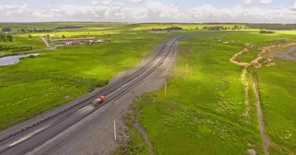 Podlewacz. Samochód do podlewania dróg. Kontrola lotnicza ciężarówki. Przechylona wywrotka przewożąca węgiel wzdłuż wiejskiej drogi. Ciężarówka porusza się po brudnej drodze. Ciężarówka jedzie pustą wiejską drogą — Wideo stockowe