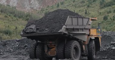 Kömür madenciliğinde büyük kamyonları yavaş çekimde vurmak ve taşımacılık üretimi. Kocaman bir çöp kamyonu kömür taşıyor. Açık maden ocağı. Taş taşıyan büyük bir çöp kamyonu. Madencilik endüstrisinde kömür işi