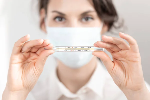 Vrouwelijke arts in medisch masker close-up toont glas thermometer met hoge temperatuur. Concept ncov 2019. Verpleegster toont thermometer van coronavirus geïnfecteerd — Stockfoto