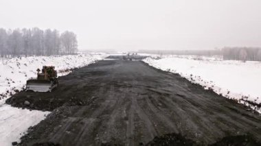 Yol manzarası kışın işe yarar. Kışın kırsalda yol yapımı için ağır inşaat ekipmanları var. Kış yolu üzerindeki manzarayı göster