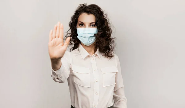 Gemaskerde vrouw stopt met handgebaar. Influencer Girl blogger in medisch masker praat over covid-19, coronavirus. Meisje met medisch masker stopt 2019-nCov — Stockfoto