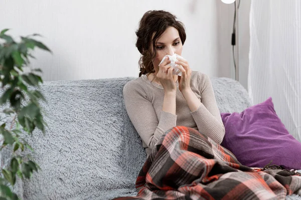 Zieke vrouw verdacht van covid-19, thuis in bed, meet de temperatuur en niest. Zieke vrouw onder de deken. Meisje in quarantaine met vermoedelijk coronavirus — Stockfoto