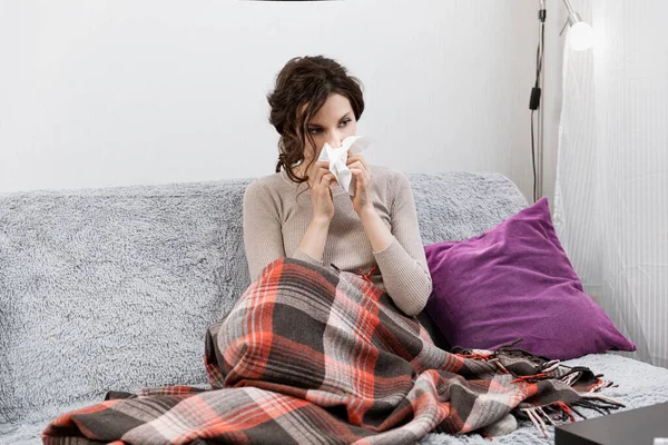 Zieke vrouw verdacht van covid-19, thuis in bed, meet de temperatuur en niest. Zieke vrouw onder de deken. Meisje in quarantaine met vermoedelijk coronavirus — Stockfoto