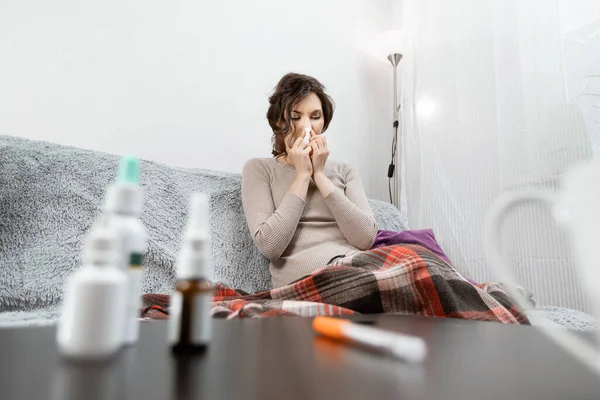 Zieke vrouw verdacht van covid-19, thuis in bed, meet de temperatuur en niest. Zieke vrouw onder de deken. Meisje in quarantaine met vermoedelijk coronavirus — Stockfoto