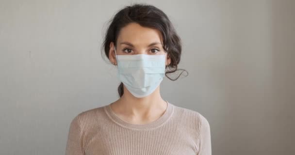 Young woman shows how to wear protective medical mask. Beautiful girl shows protective mask during pandemic. Health care and medical concept. Close up portrait girl in protective mask — Stock Video