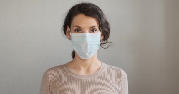 Mujer joven muestra cómo usar máscara médica protectora. Hermosa chica muestra máscara protectora durante la pandemia. Salud y concepto médico. De cerca chica retrato en máscara protectora — Vídeos de Stock