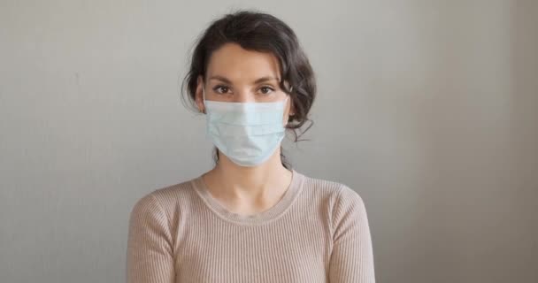 Young woman shows how to wear protective medical mask. Beautiful girl shows protective mask during pandemic. Health care and medical concept. Close up portrait girl in protective mask — Stock Video