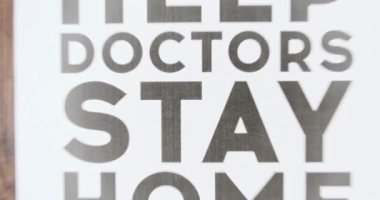 Yavaş çekim, yazıyla posteri azalt, lütfen doktorlara yardım et, evde kal. Üzerinde yazı olan konsept poster evde kalın, ağır çekim