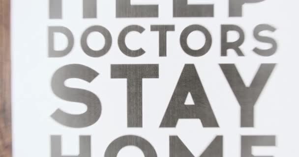 Zeitlupe, Plakat mit der Aufschrift "Bitte helfen Sie Ärzten, bleiben Sie zu Hause". Konzeptplakat mit der Aufschrift Daheim bleiben, slow-mo — Stockvideo