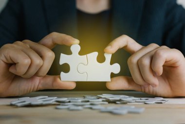 Yapboz 'u ışık efekti, iş çözümleri, başarı ve strateji konseptine bağlayan çalışan kadınların elleri