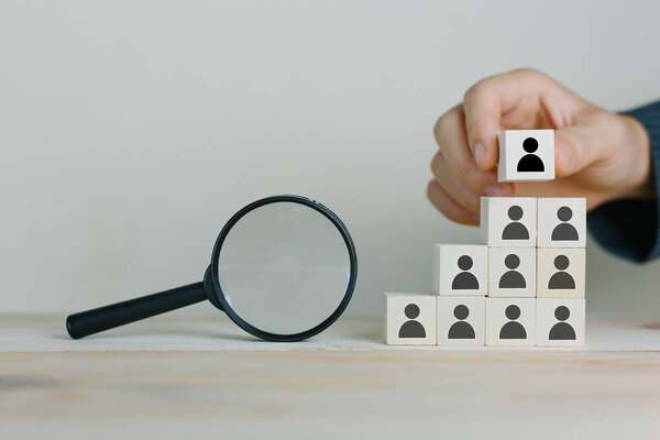 Hand woman putting wood cube block on top pyramid,Human resources, social networking, assessment center concept, personal audit or CRM concept - recruiter complete 