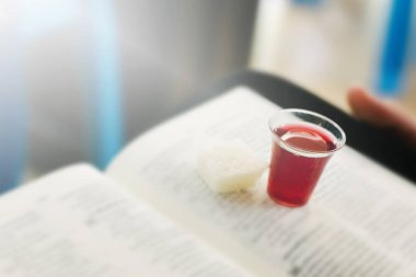 Kutsal ayinde kırmızı şarap bardağını tutan eller.