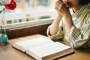 Genç bir kadın oturuyor ve İncil 'de dua ediyor. Kopya alanı