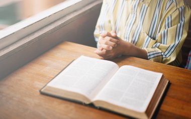 Genç bir kadın oturuyor ve İncil 'de dua ediyor. Kopya alanı