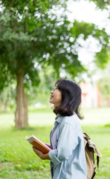 眼鏡をかけたアジアの大学生や高校生の少女の肖像画で 大学の木の下にコピースペースがある本を読んでいます 教育とオタクスマート人々の概念 — ストック写真