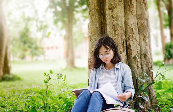 眼鏡をかけたアジアの大学生や高校生の少女の肖像画で 大学の木の下にコピースペースがある本を読んでいます 教育とオタクスマート人々の概念 — ストック写真