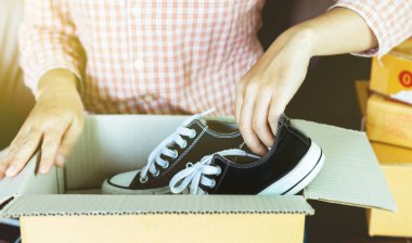 Çevrimiçi satış, e-ticaret konsepti, evdeki kutuda ayakkabı paketleyen genç bir işletme sahibi..