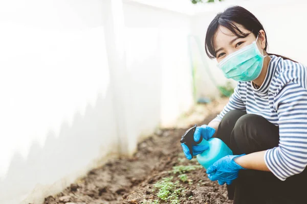 The gardener is happy in gloves and wears a protective mask in the garden at home. stay at home concept.