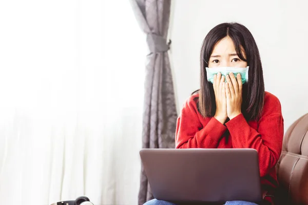 Young woman in mask sitting at the sofa in home office.stay at home concept.