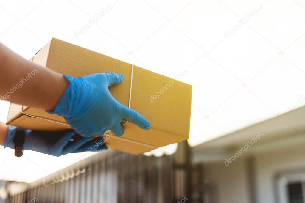 The Postman wearing the protective gloves Deliver to home.Asian woman receiving boxes from postman . Postman giving.stay at home concept.