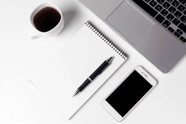 Taza con café, Cuaderno con pluma y teléfono inteligente cerca del ordenador portátil — Foto de Stock