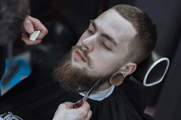 Młody Brodaty Mężczyzna Obcinający Włosy Przez Fryzjera Temat Zakładu Fryzjerskiego — Zdjęcie stockowe