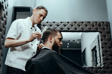 BARBERshop teması. BARBER BİR çift makas tutar ve bir COMB ve BARBER mağazasındaki müşteriyi paylaşır. BARBER Kıllı Sandalyesinde oturan Sakallı Adam
