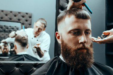 BARBERshop teması. BARBER BİR çift makas tutar ve bir COMB ve BARBER mağazasındaki müşteriyi paylaşır. BARBER Kıllı Sandalyesinde oturan Sakallı Adam