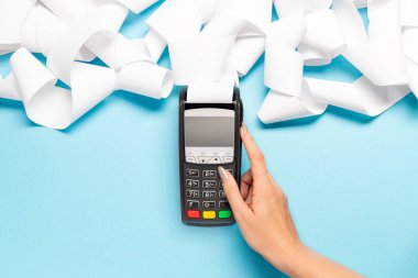 Mavi arka planda uzun kasiyer bandı olan pos terminal. Kadın eli bir posizyon düğmesine basar. alışveriş teması
