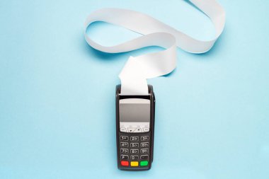 Mavi arka planda uzun kasiyer bandı olan pos terminal. alışveriş teması