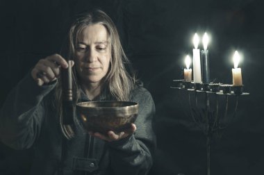 Cadı Tibet kâsesiyle oynar. Menoranın üzerindeki mumlar solda yanıyor.