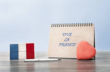   Congratulations on Bastille day. A heart is attached to an open Notebook. Next to it is the flag of France, made up of cubes. clipart