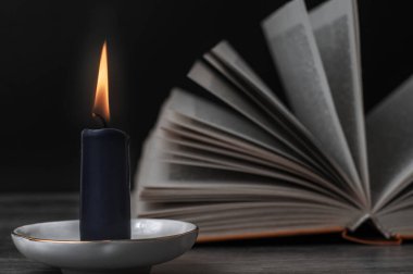 Yanan bir mum ve açık bir kitap. Cadılar için ayarlandı.